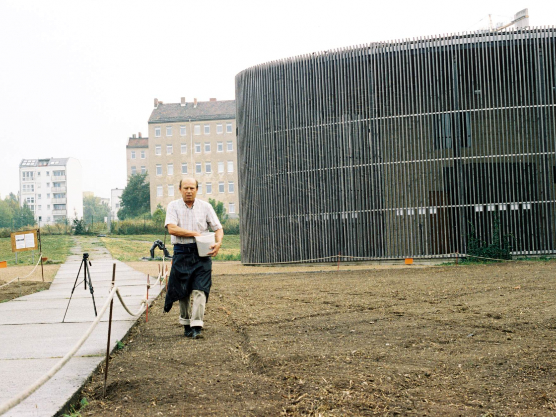 Mann streut Roggensamen auf das Feld an der Kapelle der Versöhnung