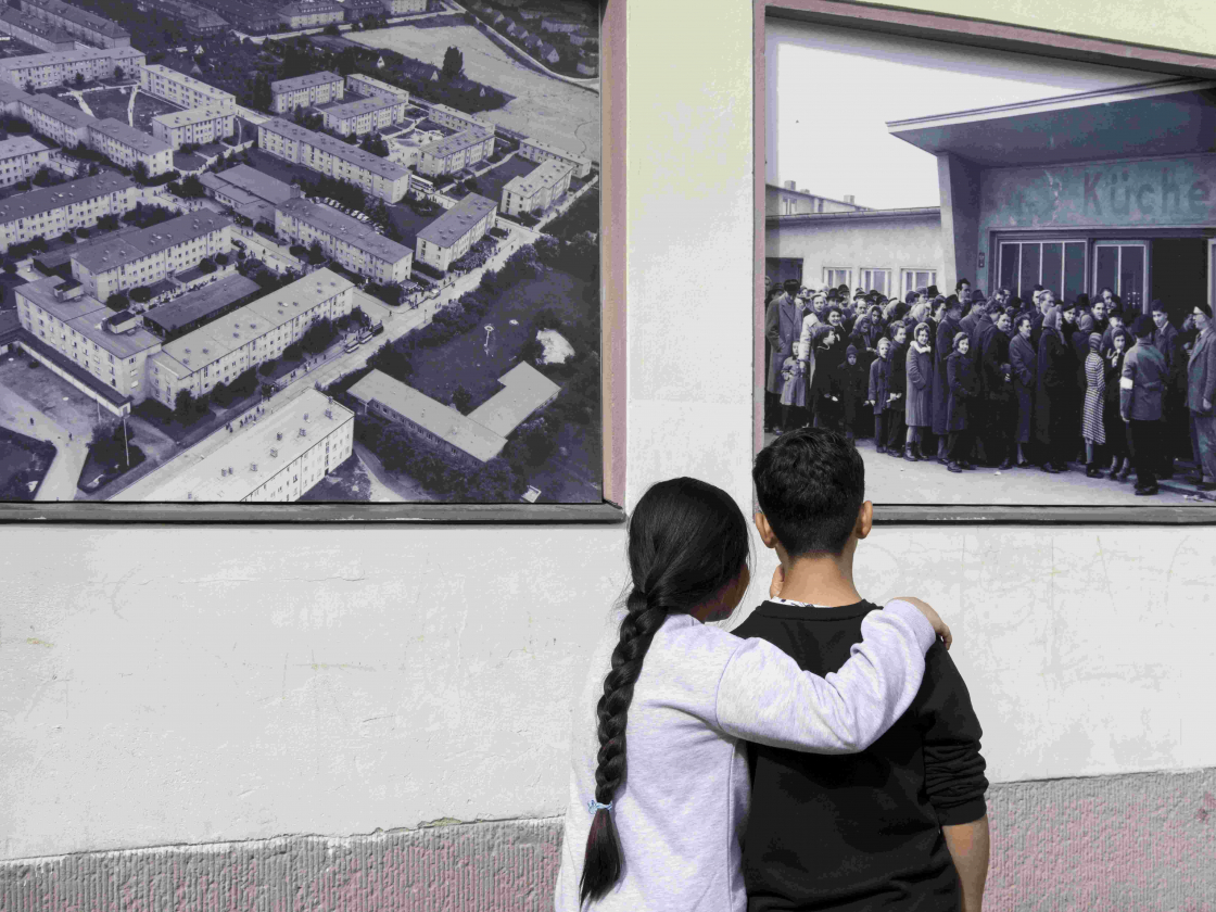 Foto von zwei jungen Menschen vor historischen Fotos.