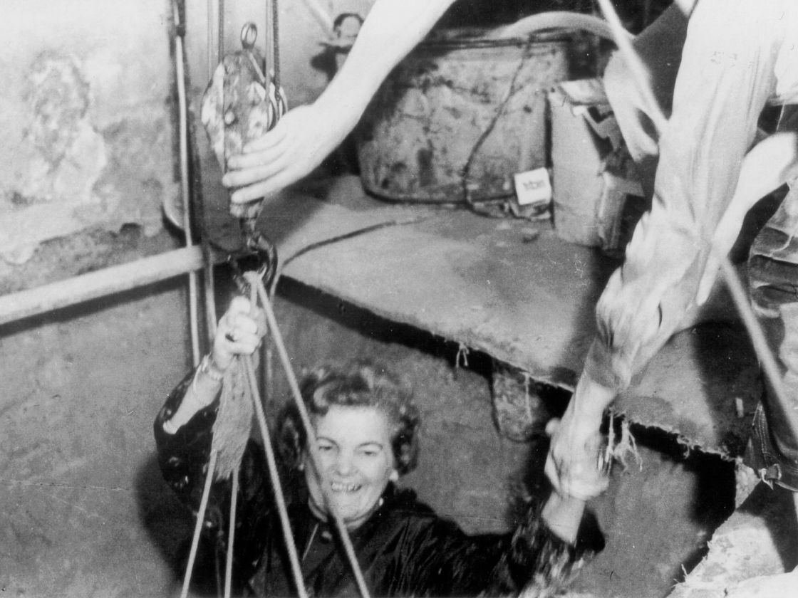 Frau wird aus einem Tunnel gerettet von einem Fluchthelfer.