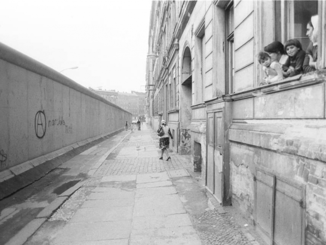 Kinder schauen aus einem Fenster eines Gebäudes an der West-Berliner-Mauer