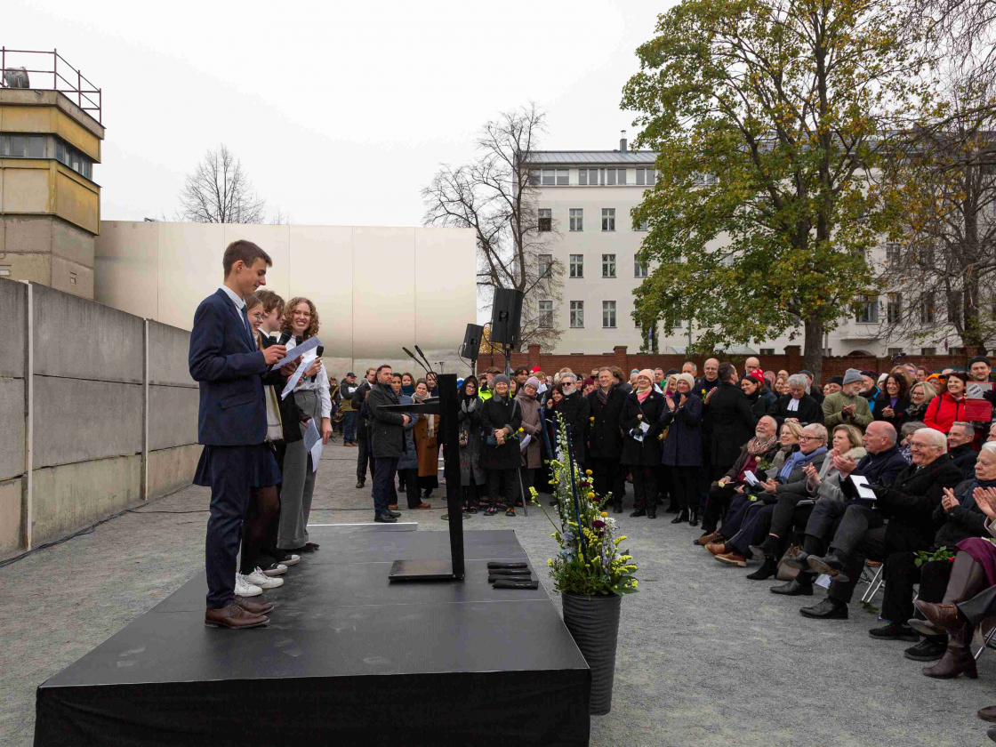 Drei Jugendliche halten eine Rede vor großem Publikum an der Gedenkstätte Berliner Mauer.