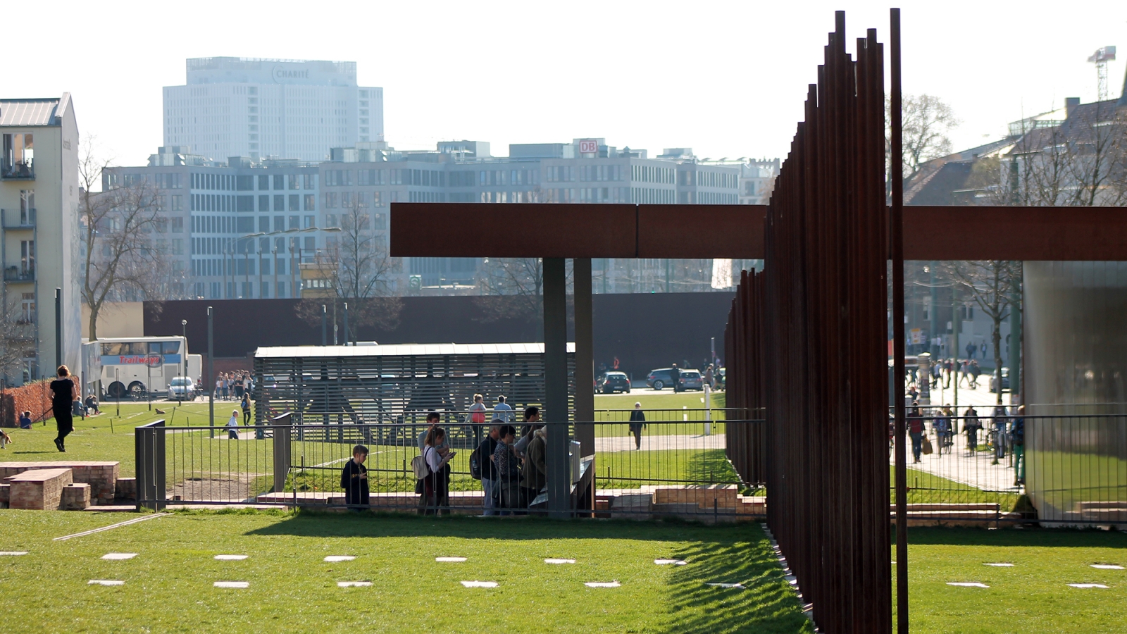 Blick auf das Grenzhaus mit Besuchenden. Im Vordergrund sind die Stahlstelen der Mauernachzeichnung zu erkennen.n